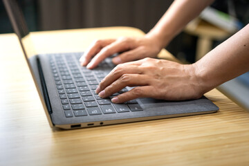 Action of a businessperson is typing on the modern design laptop keyboard to input or program data, business working concept scene. Close-up and selective focus at human hand's part.