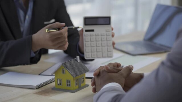 A home salesman is preparing and reviewing a purchase contract for a prospective client. The concept of selling housing estates and real estate .4k