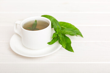 Cup of mint tea on table background. Green tea with fresh mint top view with copy space