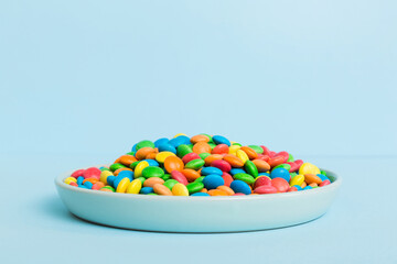 Multicolored candies in a bowl on a colored background. birthday and holiday concept. Top view with copy space