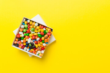 Set of different sweet candy in a paper box with a satin ribbon on a colored background. Holiday concept