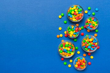 different colored round candy in bowl and jars. Top view of large variety sweets and candies with copy space