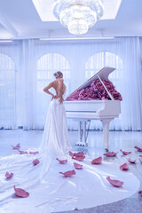 Beautiful woman with white piano and peonies flowers in white studio