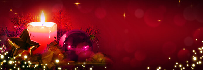 Red Advent candle with Christmas decorations isolated on blur bokeh background.