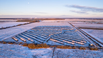 Aerial view of the solar farm in a winter sunny day. Flight low over the white fields.