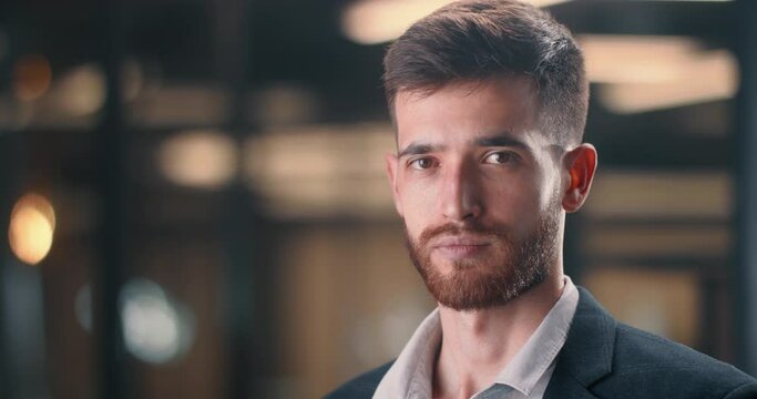 A successful businessman in the office builds his business and increases his financial viability. Cinematic shot of a male businessman in front of office lights. Successful millennial.