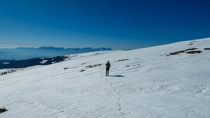 Woman hiking in snow covered landscape near Ladinger Spitz, Saualpe, Lavanttal Alps, Carinthia, Austria, Europe. Trekking in Austrian Alps in winter on a sunny day. Ski touring and snow shoe tourism