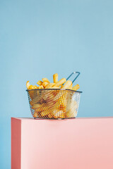 close-up of french fries in a basket on a pink cube on a blue background with free space for text