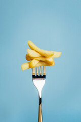 close-up of french fries chopped on a fork on a blue background