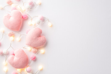 Valentine's Day concept. Top view photo of fluffy heart shaped toys light bulb garland and soft pompons on isolated white background with copyspace