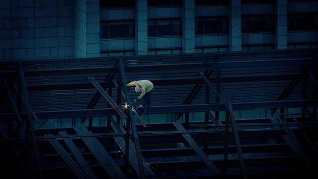 Man Solders Beams On Building In The Evening - Difficult Job Concept
