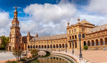 Fototapeta na wymiar Panorama of the Spain Square Plaza de Espana in Seville, with bridges over the canal, lake, fountain, towers and main entrance to the building. Example of Moorish and Renaissance revival.