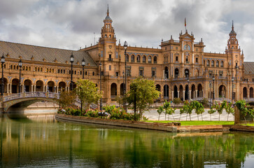 Fototapeta na wymiar Amazing Plaza de Espana in Seville, Spain. Water reflection of the palace buildings on the adjacent canal. One of major Spanish tourist attractions. Regionalism architecture.