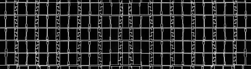 Abstraktes Muster von vielen gestapelten silbernen Metallteilen vor schwarzem Hintergrund