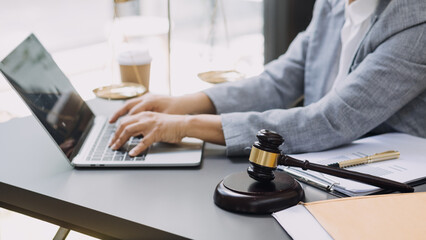 Justice and law concept.Male judge in a courtroom with the gavel, working with, computer and docking keyboard, eyeglasses, on table in morning light