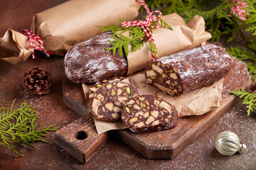 Chocolate salami cake with pistachio nuts, walnuts and cookies. Traditional delicious homemade Christmas dessert. 
