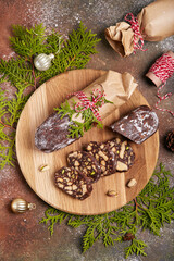 Chocolate salami cake with pistachio nuts, walnuts and cookies. Traditional delicious homemade Christmas dessert. 