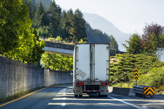 Transport truck on a highway going under an overpass, driving to Porteau Cove, Sea to Sky Highway, South of Squamish; British Columbia, Canada