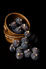 Fichi in una ciotola di terracotta, su sfondo nero.