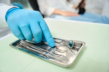 Experienced dentist selecting tool for patient examination