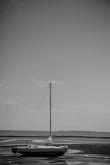 Sailboat lying in the mud at low tide in the Atlantic Ocean near the Ile de Ré