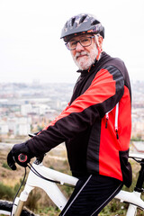 Naklejka premium portrait of older cyclist with bike in sports clothes
