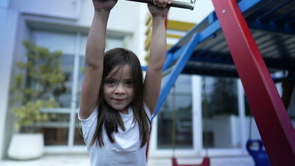 Small girl holding into metal bar at playground child hand holds on monkey bar