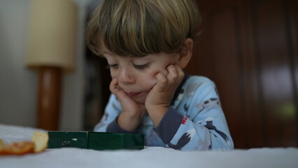 Little boy eating tangerine fruit in the morning wearing pajamas