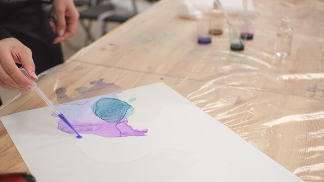 a girl uses an alcohol ink pipette to create a creative drawing. High-quality shooting in 4k format