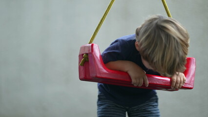 Obraz premium Child twisting and turning at playground swing playful little boy having fun by himself outside at park