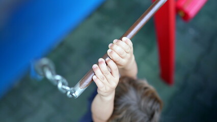 Child trying to reach metal bar at playground kid showing effort reaching for monkey bar