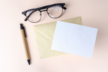 Letter mock up template, envelope with a white blank card, pen and glasses, office top view.
