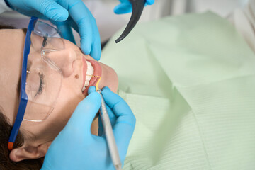 Woman undergoing interproximal cleaning conducted by doctor