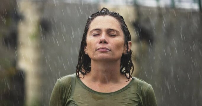 Close up of Woman 40s Face in the rain, Natural Beauty Face Female with drop rain on face. Woman relax outdoor in autumn rainy day. Health care, authenticity, sense of balance zen and calmness.