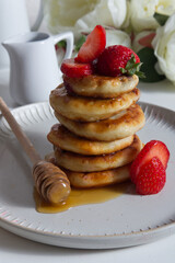 Cottage cheese pancakes with strawberries sprinkled with honey