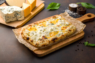 Roman pizza four cheeses on Roman dough, pinsa on dark brown table