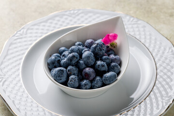  blueberry  on a white plate on stone table macro close up