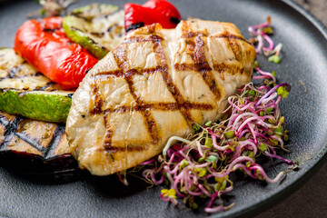 Grilled chicken Breasts with grilled vegetables on black plate