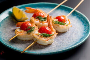 tiger shrimp kebab with mini tomatoes on blue plate macro close up