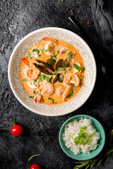 Tom Yam soup with shrimps and seafood on dark plate top view vertical