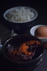 White rice with grilled chicken and boiled eggs on a dark background