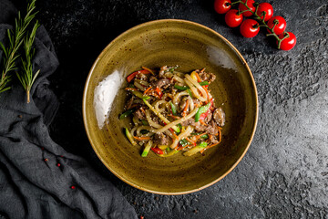 beef wok noodles with vegetables on dark stone table top view