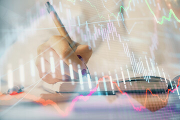 Multi exposure of woman's hands making notes with forex graph hologram. Concept stock market...