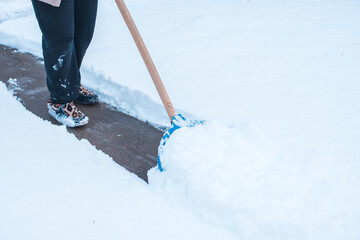 Winter problems concept . Woman digging snow with shovel at yard. Lady standing with blue shovel...