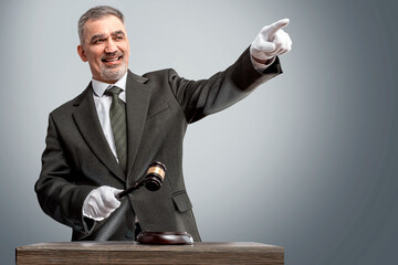 Auctioneer, salesperson with gavel at public auction. Senior male barker in formal elegant suit with auction hammer for close the bidding - obrazy, fototapety, plakaty