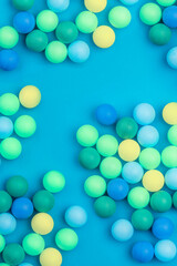 Abstract colored balls background. Multi-colored taw toy scattered on bright paper. Base for design nice backdrop, wallpaper, poster. Noisy surface texture