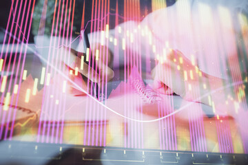 Financial forex graph displayed on hands taking notes background. Concept of research. Double exposure