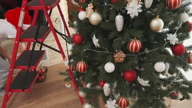 A little boy decorates a Christmas tree and puts a Christmas star on top. Video 4k
