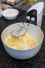 Mix the butter with the sugar in a white bowl to bake the cake. Blender beater closeup. Selected focus.