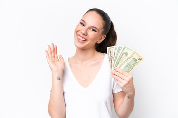 Young caucasian woman taking a lot of money isolated on white background saluting with hand with happy expression